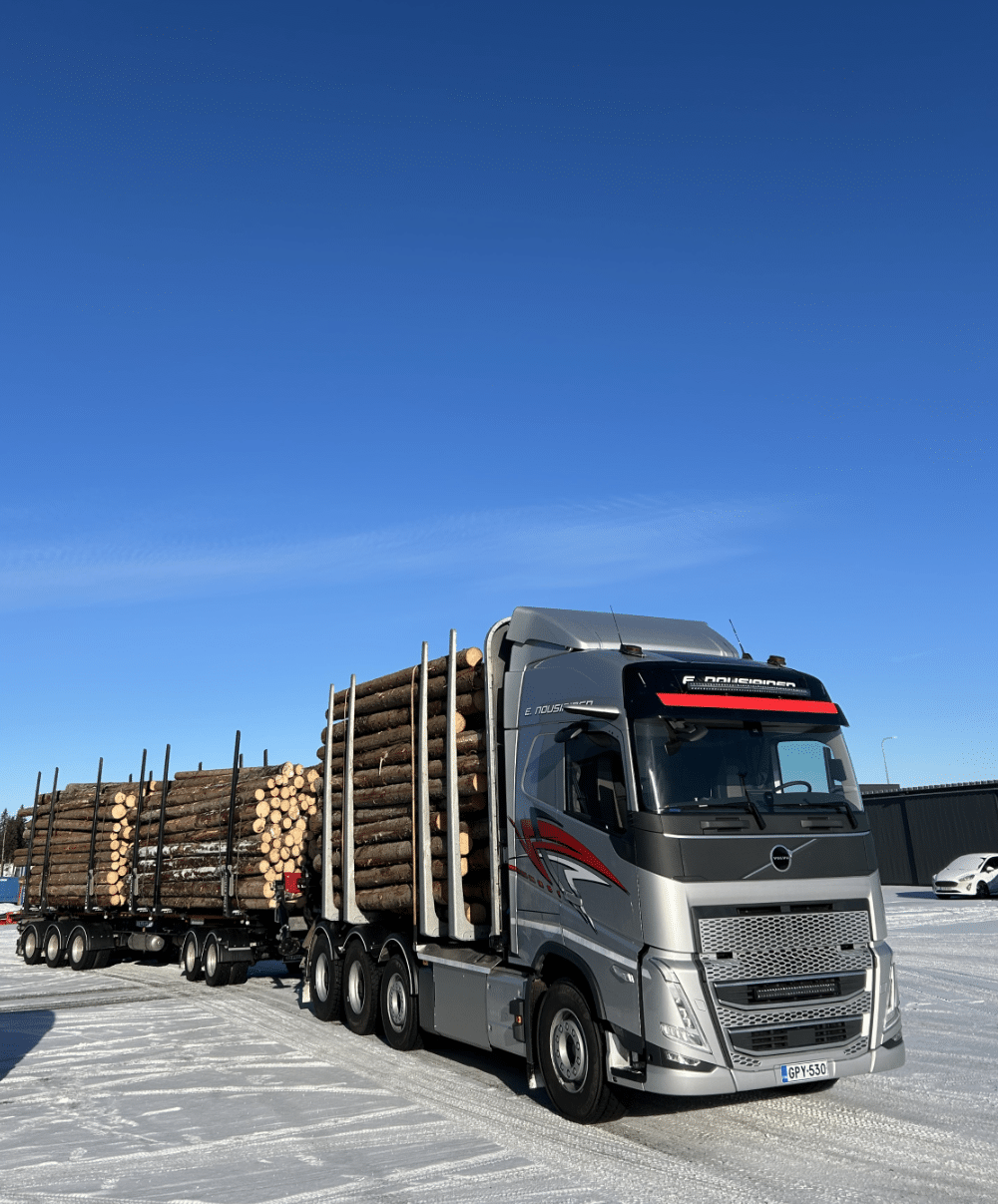 Kuljetusliike E. Nousiaisen puuauto taydessa lastissa talvisessa iltahamarassa metsatiella.